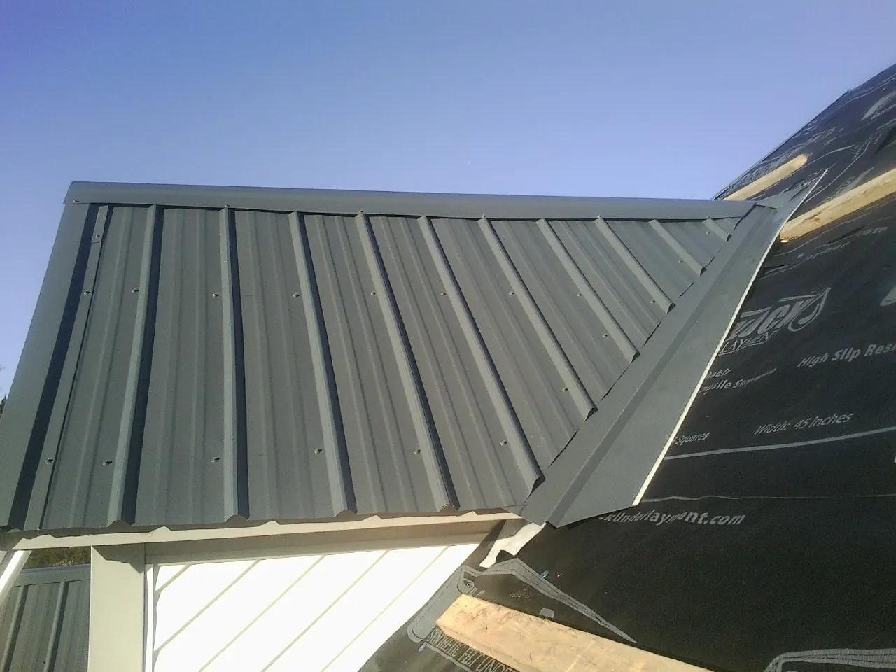 Gray metal roof panels going on over a garage gable in Hawk Run