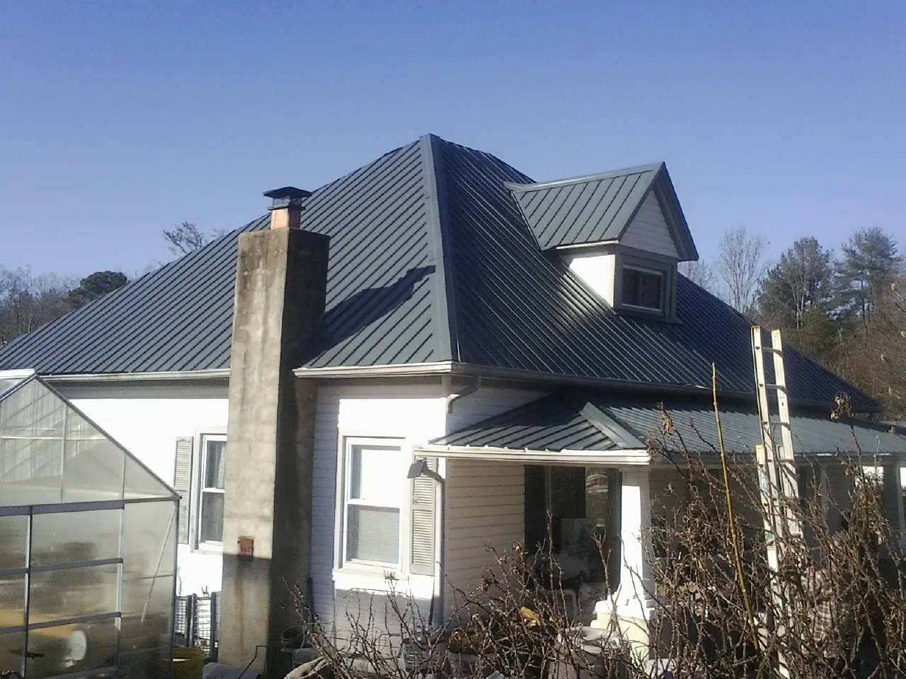 Dark blue standing seam metal roof on a white farmhouse with dormer — Slate & Tile Roof Repair by Roofing Brothers in Hawk Run