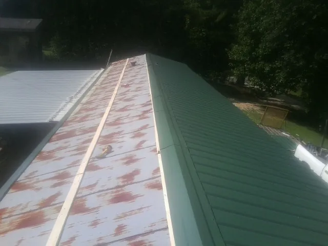 Old rusted panels beside newly installed green metal roofing — Wind Damage Roof Repair by Roofing Brothers in Hawk Run