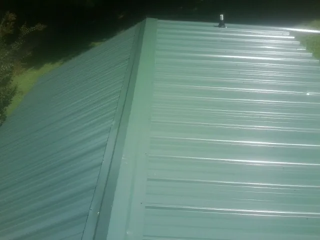 New green metal panels meeting at the ridge of a roof — Flat Roof Repair work by our crew in Hawk Run