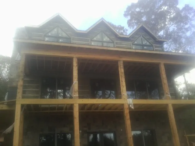 Dormers and porch framing on a large log home under construction — Roof Coating work by our crew in Hawk Run