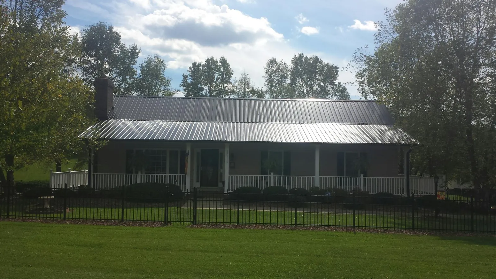 Gray metal roof on a brick ranch with a full width front porch — Gutter Guard Installation work by our crew in Hawk Run
