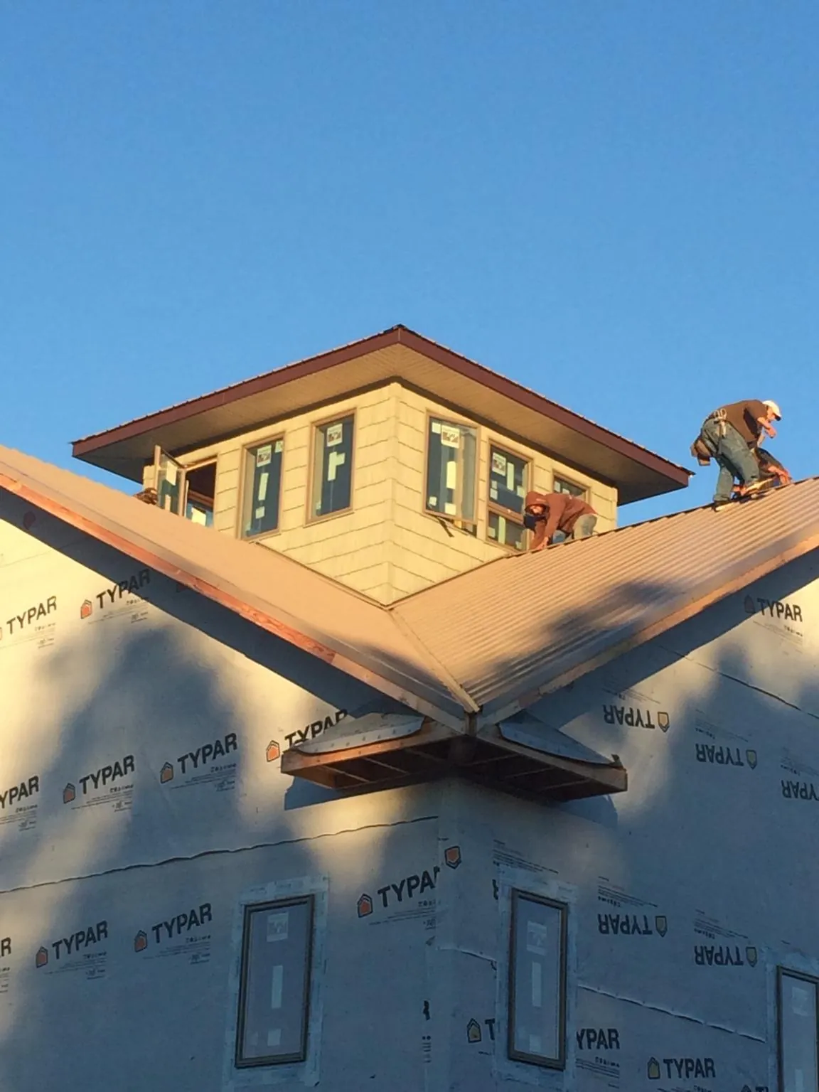 Roofers working around a rooftop cupola on a new metal roof at sunset — Roof Waterproofing in Hawk Run by Roofing Brothers